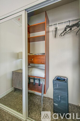 A bedroom with a bed and a wardrobe with clothes hanging on it.