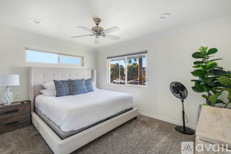 A bedroom with a large bed and a ceiling fan.