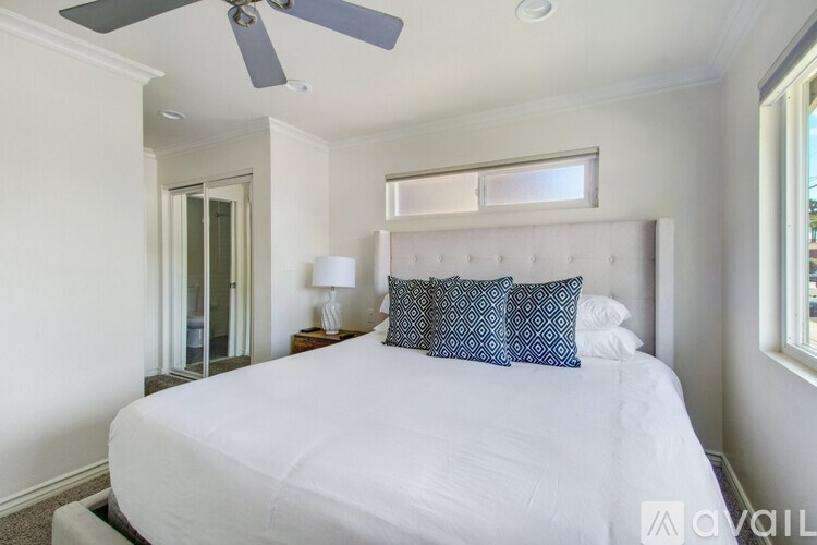 A bedroom with a white bed and a ceiling fan.