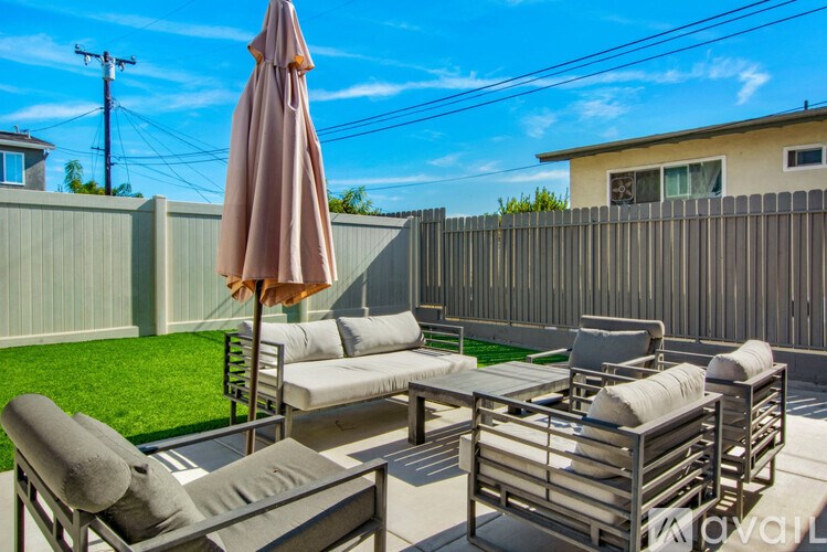 A patio with a table, chairs, and an umbrella.