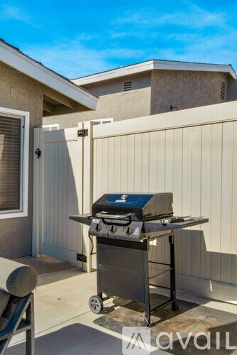 A grill is on a patio in front of a house.