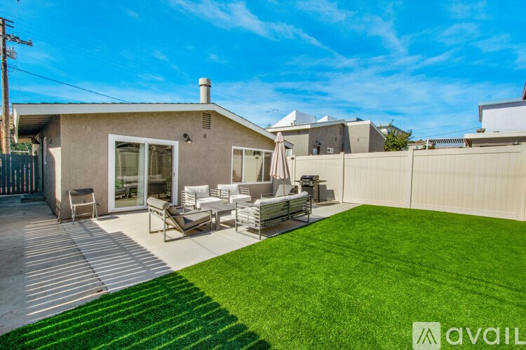 A house with a green lawn and a patio with chairs and a table.