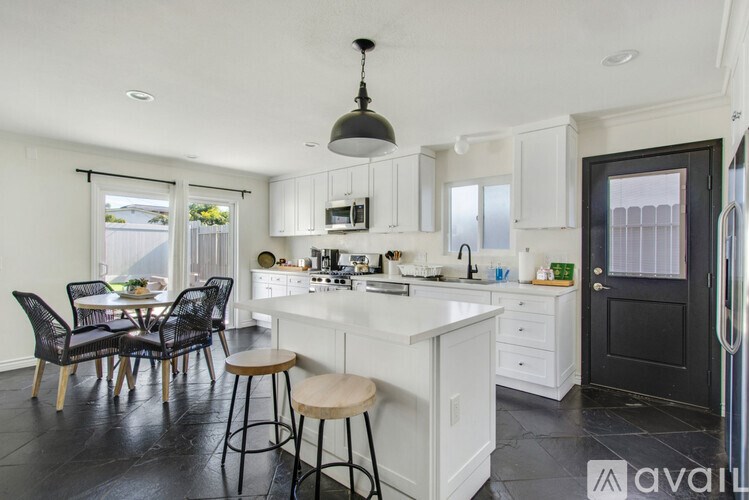 A kitchen with white cabinets and black chairs.