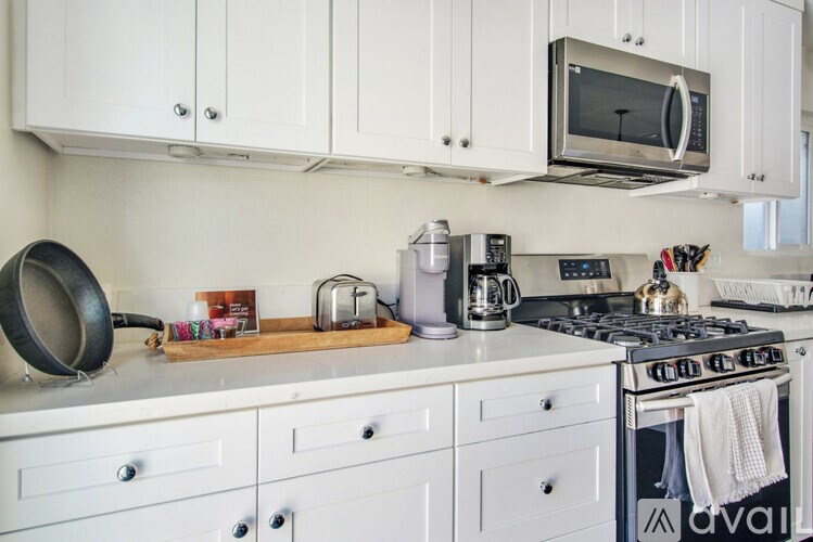 A kitchen with white cabinets and a stove top oven.
