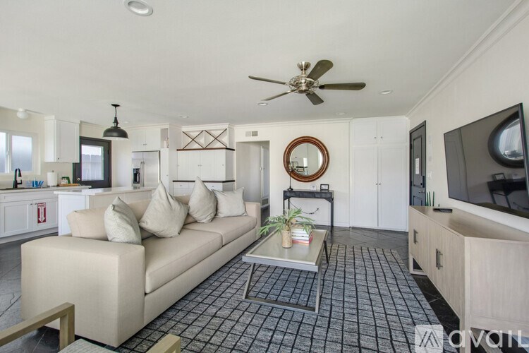 A living room with a beige couch, a coffee table, and a ceiling fan.