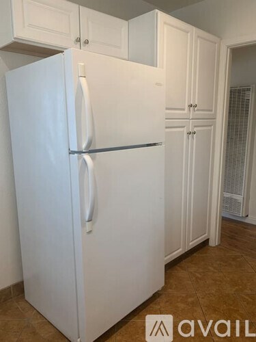 A white fridge in a kitchen with white cabinets.