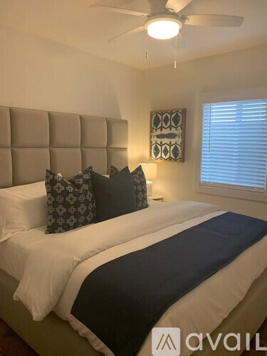 A bedroom with a bed, pillows, and a ceiling fan.