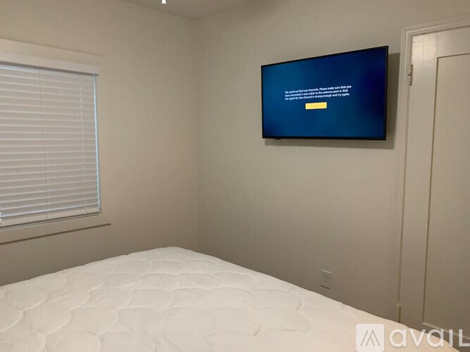 A bedroom with a mattress and a flat screen TV mounted on the wall.