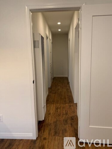A hallway with white walls and wood flooring.