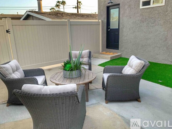 A patio with grey wicker furniture and a green plant on a table.
