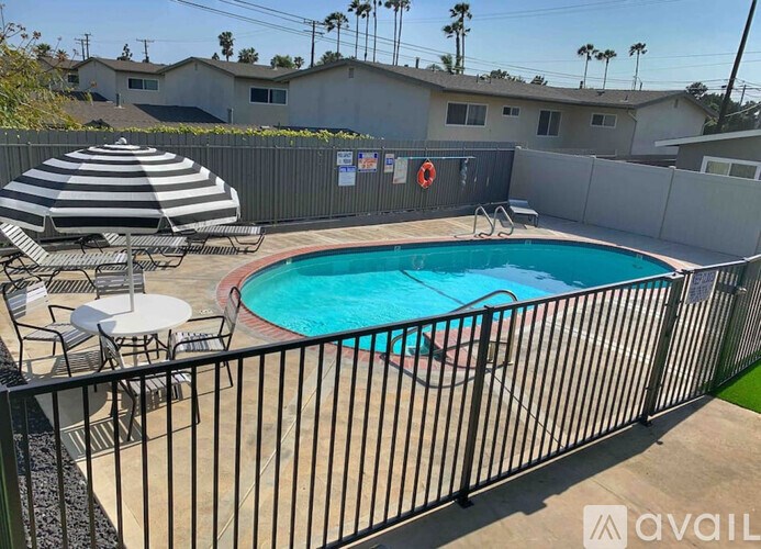 A pool surrounded by a black fence with a white umbrella and a red life preserver.