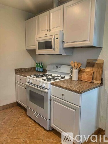 A kitchen with a white stove and oven, a microwave above it, and a counter with a toaster and wooden utensils.