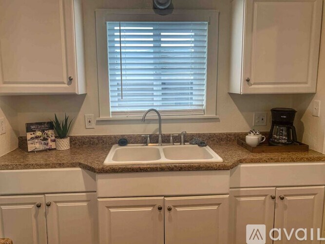 A kitchen with a sink and a window with blinds.