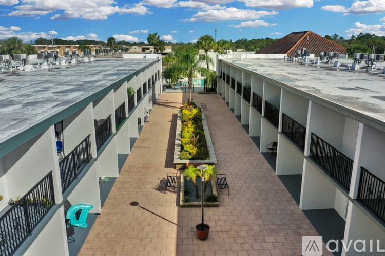 A sunny day at the rooftop of a building with a long walkway and potted plants.