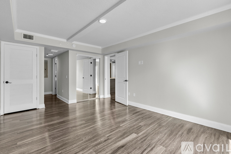 A spacious room with wooden flooring and white walls.