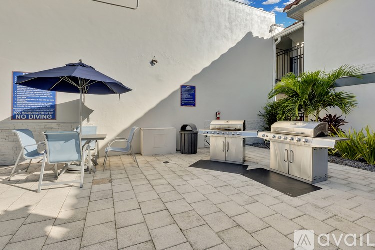 A patio with a table, chairs, and a grill.