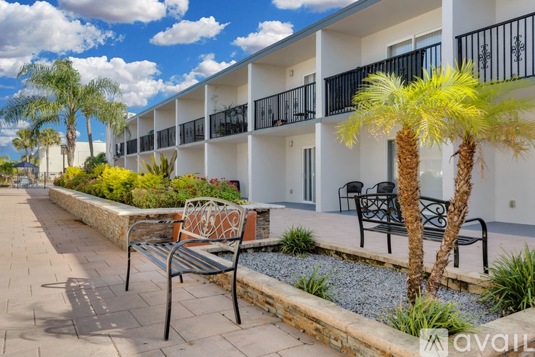 A sunny day at the outdoor patio of a building with a bench and a tree.