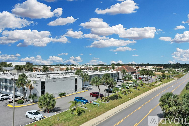 A sunny day in a suburban area with a clear blue sky and scattered clouds.