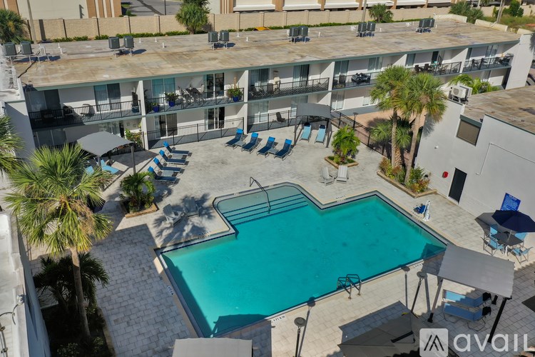 A pool surrounded by chairs and umbrellas in front of a building.