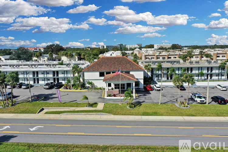 A building with a red roof is in the middle of a parking lot.