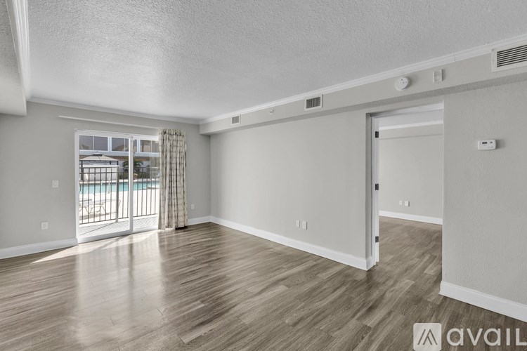 A spacious room with wooden flooring and a sliding glass door leading to a balcony.