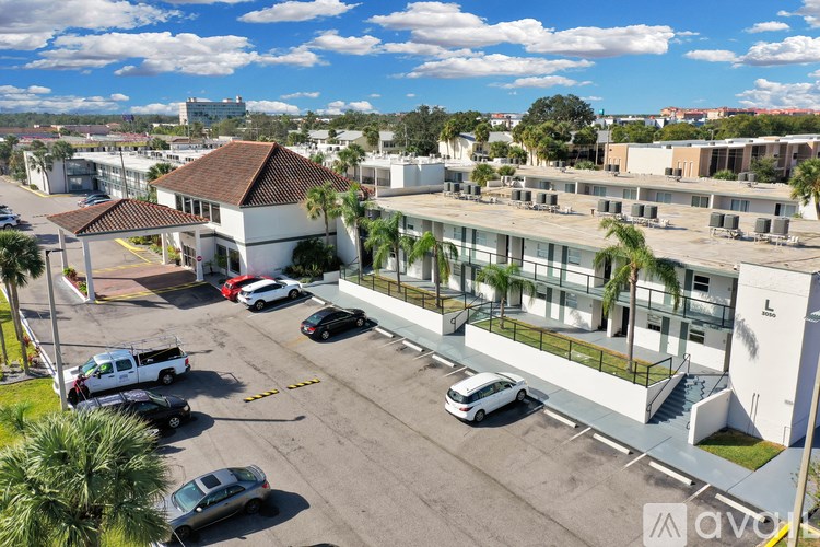 A parking lot with cars and a white building with palm trees in front.