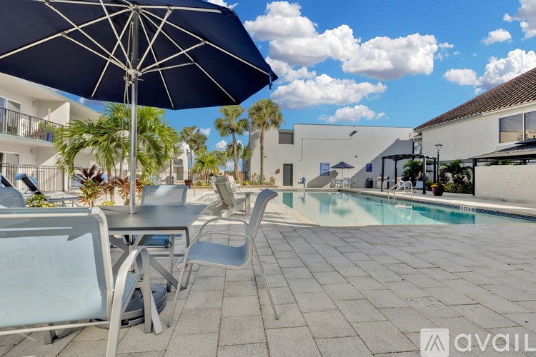 A poolside table with chairs and an umbrella is available for rent.