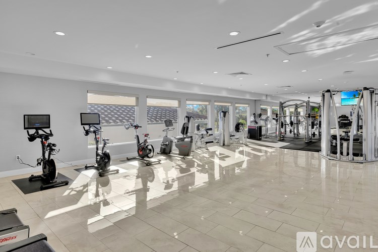 A gym with a variety of exercise equipment including treadmills, stationary bikes, and weight machines.