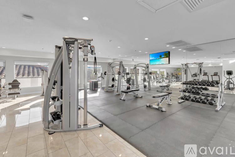 A gym with a variety of equipment including a treadmill, weights, and a television.
