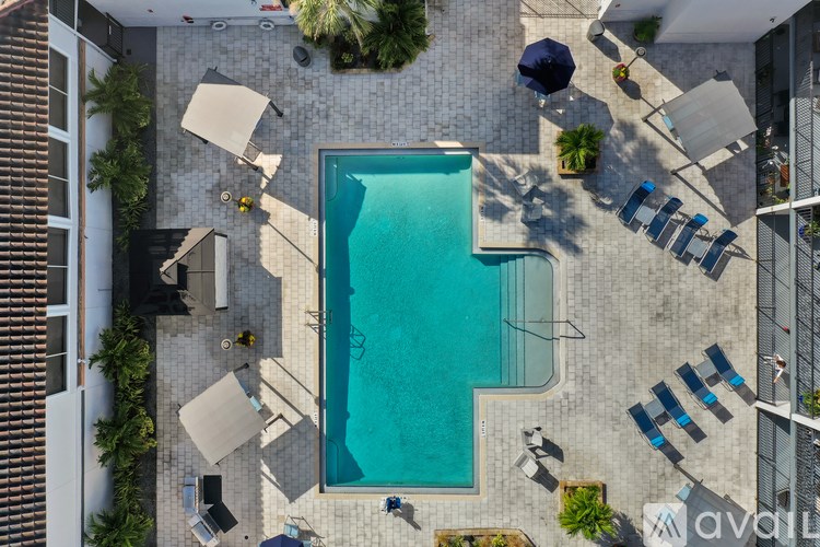 An outdoor swimming pool surrounded by sun loungers and umbrellas.