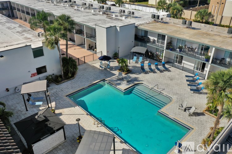 A pool surrounded by a patio and chairs.