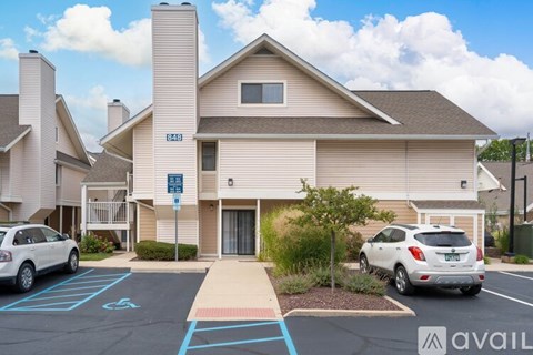 A parking lot in front of a building with a blue sign and two cars parked.