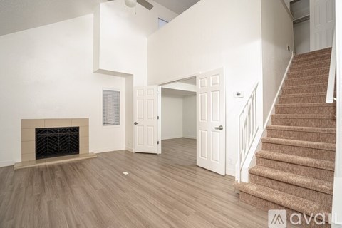 A living room with a fireplace and a staircase.