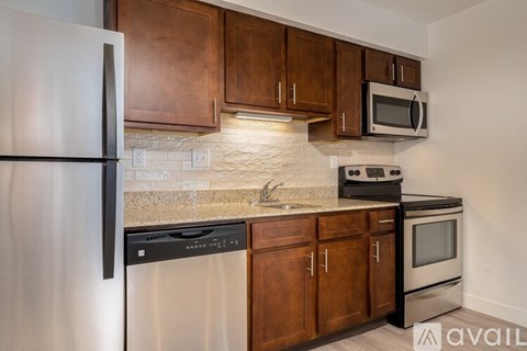A kitchen with brown cabinets and a stainless steel refrigerator.