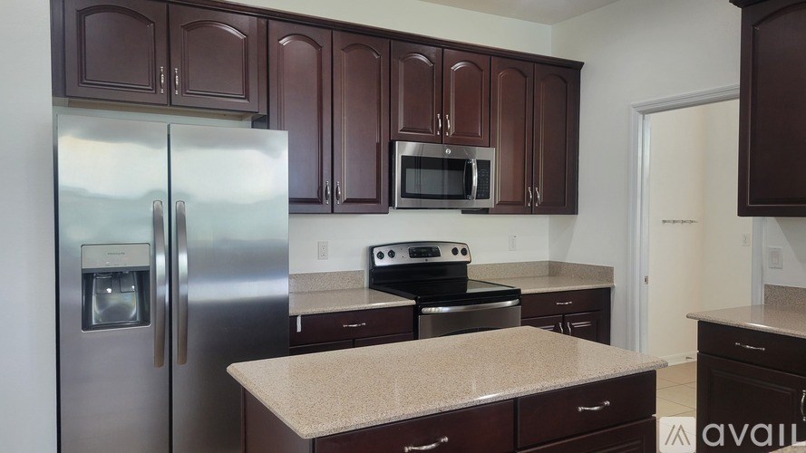 A kitchen with brown cabinets and a stainless steel refrigerator.