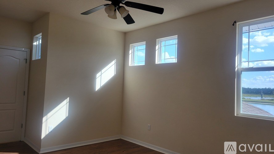 A room with a ceiling fan and three windows.