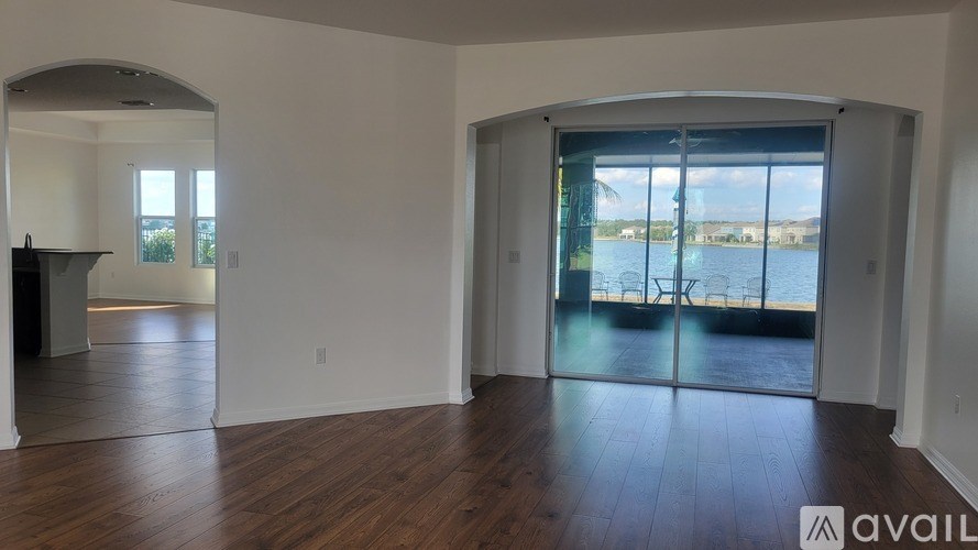 A spacious room with wooden floors and a large window overlooking a body of water.