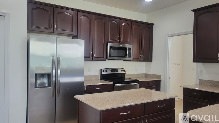 A kitchen with brown cabinets and a stainless steel refrigerator.