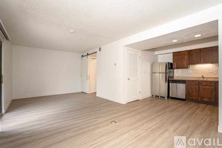 A spacious living room with a kitchen area in the background.