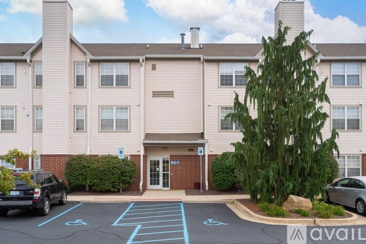 A parking lot in front of a building with a tree and a car parked.