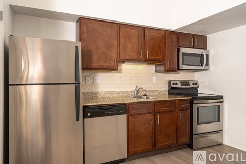 A kitchen with a stainless steel refrigerator, microwave, oven, and cabinets.