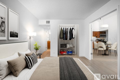 A well-lit bedroom with a large bed and a clothing rack in the closet.