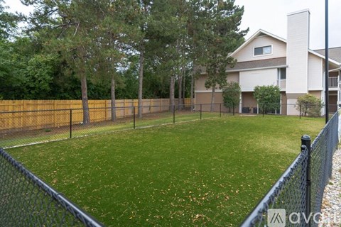 A backyard with a fence and a house in the background.