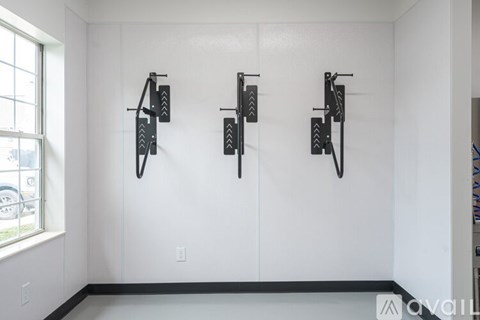 Three black bike racks are mounted on a white wall.