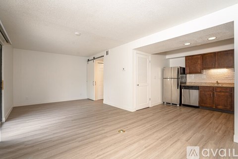 A spacious living room with a kitchen area in the background.