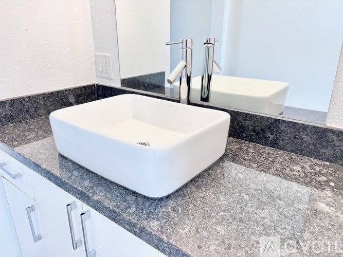 A white sink is on a granite countertop in a modern bathroom.