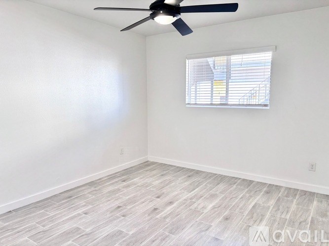 A room with a ceiling fan and a window with blinds.