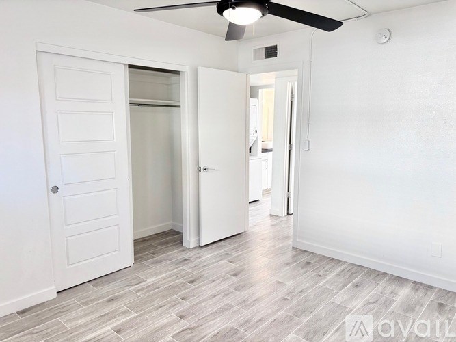 A room with a ceiling fan and a door leading to another room.