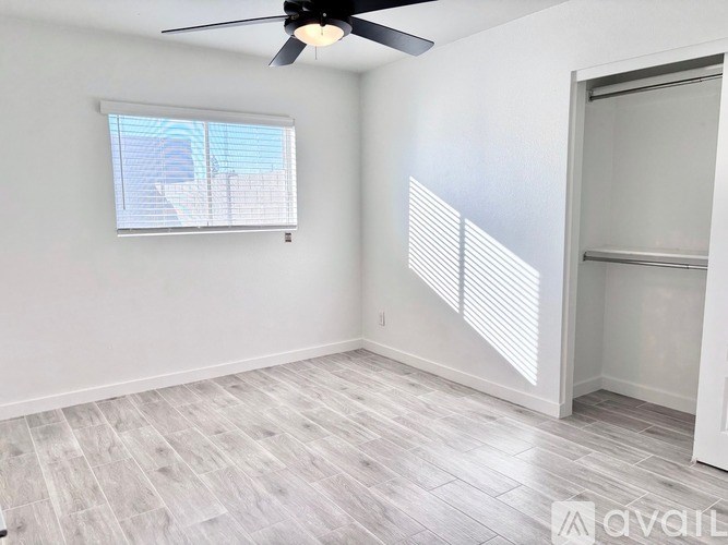 A room with a ceiling fan and a window with blinds.