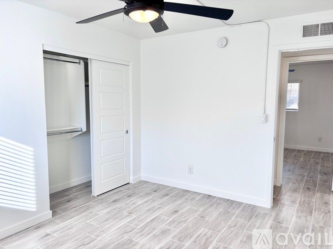 A room with a ceiling fan and a door leading to another room.